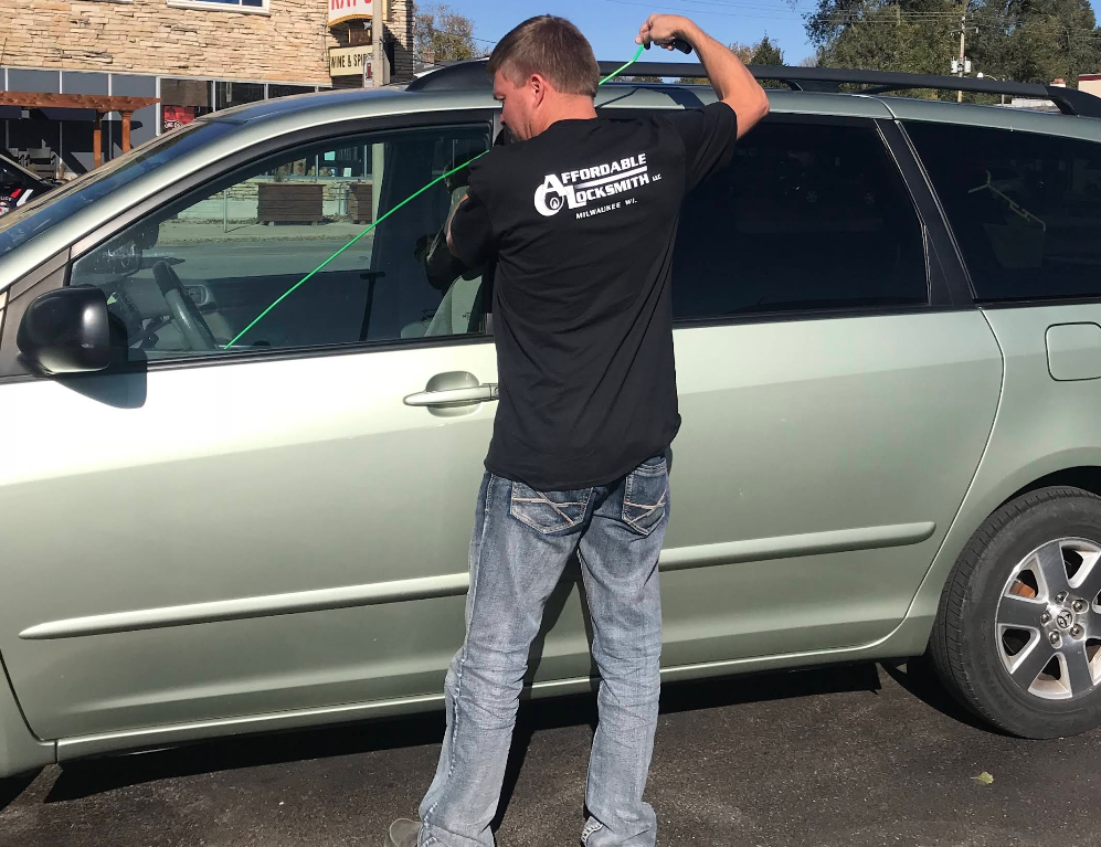 Locksmith unlocking a car door using a long arm tool