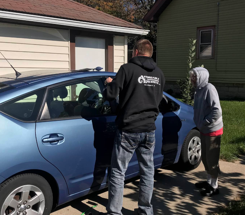 Locksmith helping a person locked out of their car in their driveway.