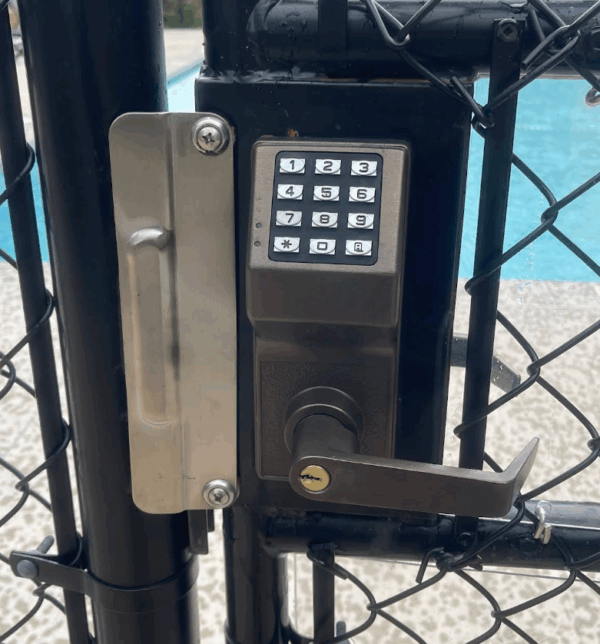 a keypad lock and latch guard on the entrance gate to a swimming pool a keypad lock and latch guard on the entrance gate to a swimming pool