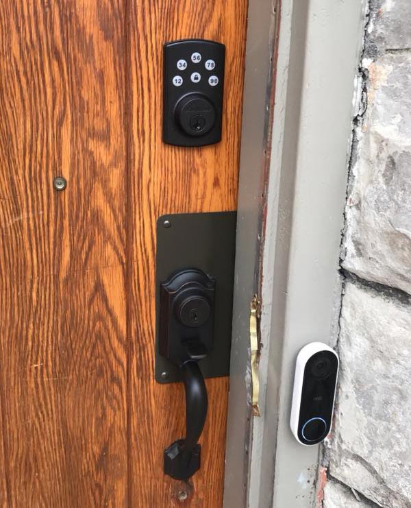 A keypad, deadbolt, thumb latch handle, and wrap plate on a door of a home.
